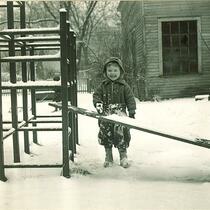 Small girl playing with snow on a slide, The University of Iowa, January 1938