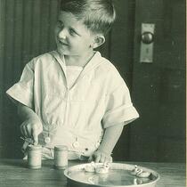 Boy playing with toy swans in a pan of water, The University of Iowa, 1920s